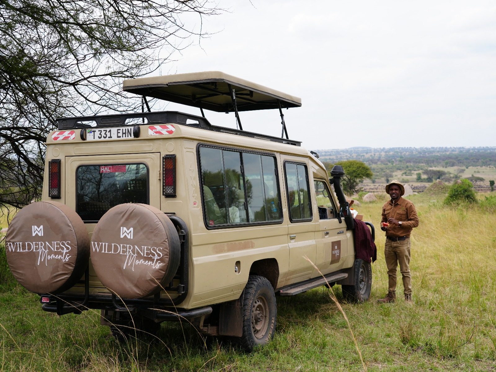 Wilderness Moments guide waving from the safari vehicle roof hatch